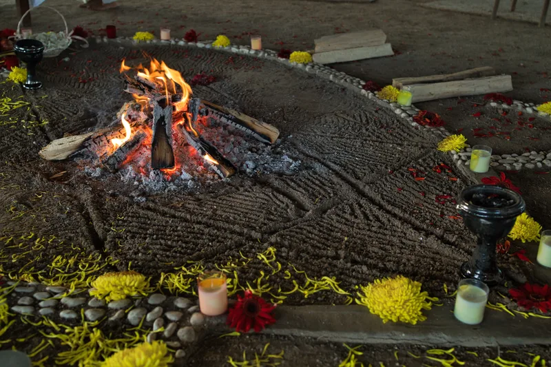 Fuego ceremonial encendido dentro de un mandala de flores