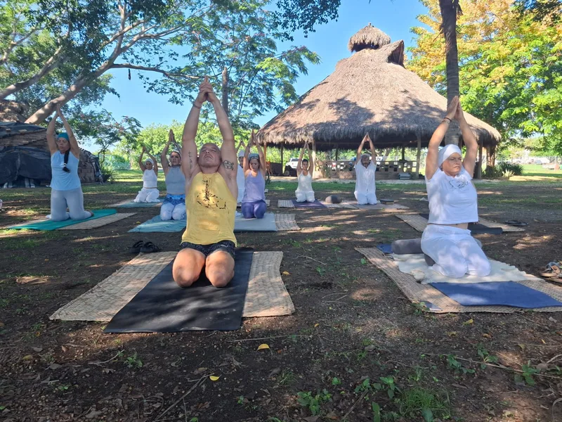 Práctica de Kundalini Yoga con los brazos elevados sobre esterillas al aire libre