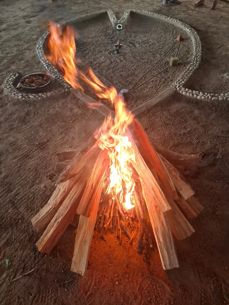Llamas del fuego ceremonial alzándose dentro del círculo trazado