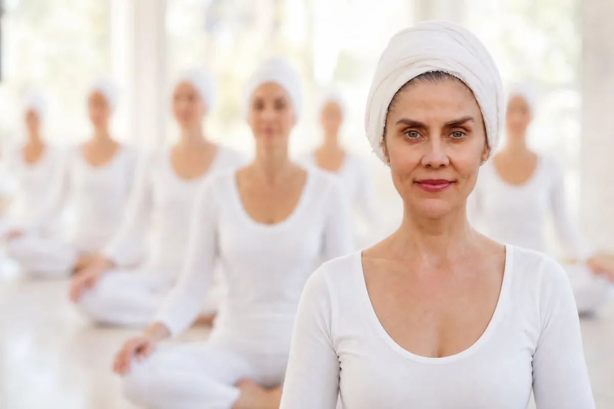 Grupo de practicantes de Kundalini Yoga vestidos de blanco y con turbante, sentados en meditación durante una clase
